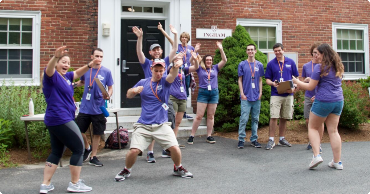 A group of camp staff joyfully celebrate in front of Ingham.